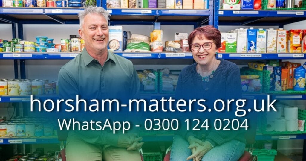 Two smiling people standing in front of shelves of donated food and household items with horsham-matters.org.uk and WhatsApp number text overlaid