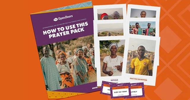 A purple prayer pack booklet with people on the cover, alongside several photo cards and small matching cards on an orange background