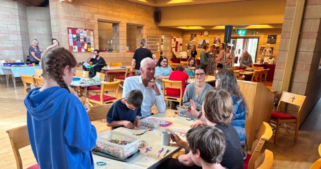 People gathered around tables making colourful crafts in a community room