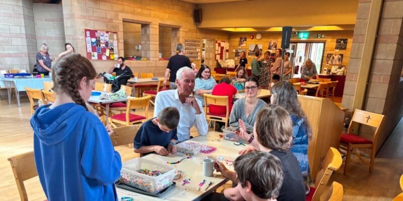 People gathered around tables making colourful crafts in a community room